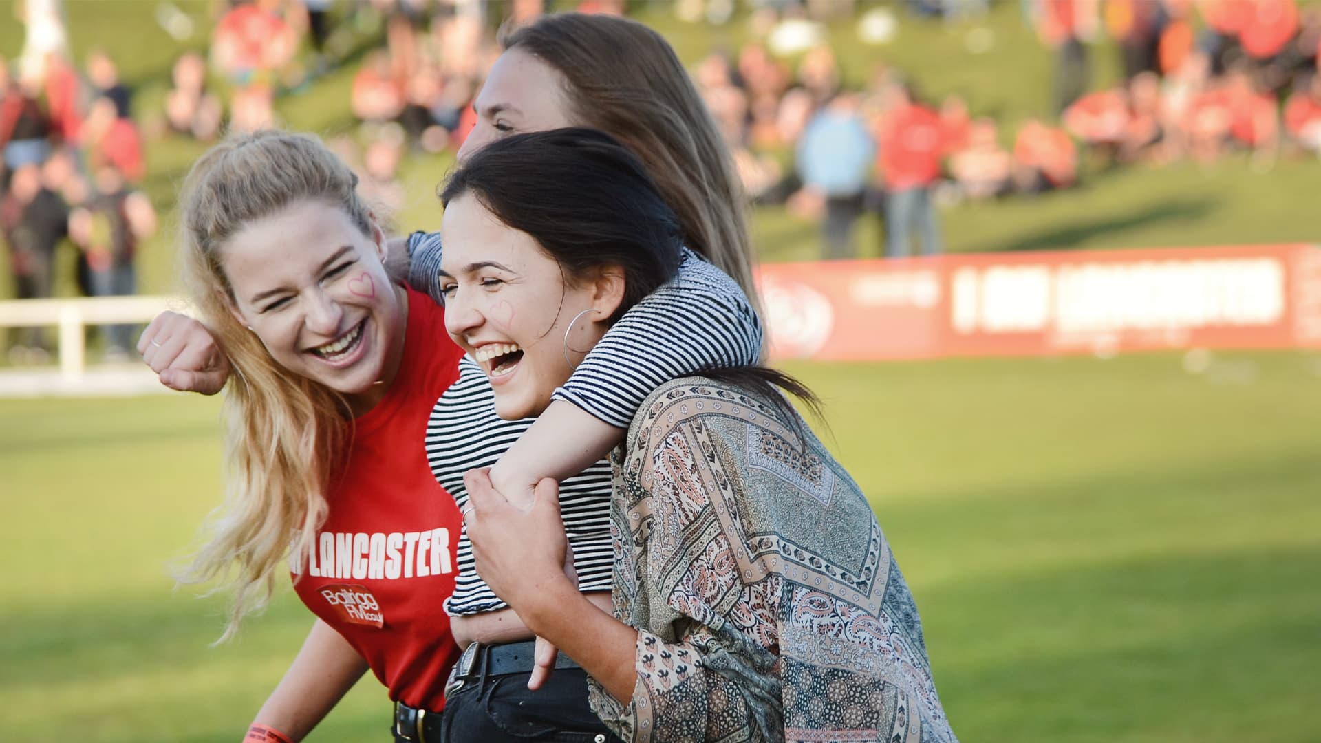 Three students hug and laugh to celebrate a Lancaster victory at the Roses.